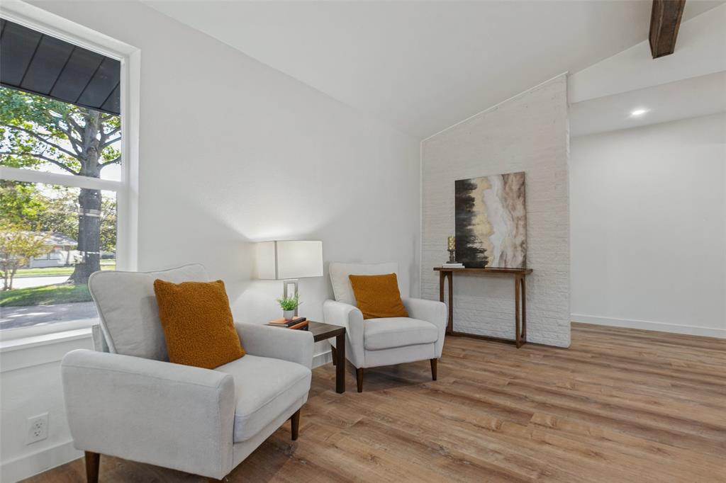 Vaulted ceilings featuring wood-finish beams, white painted brick accent wall, wood-finish flooring, and expansive windows