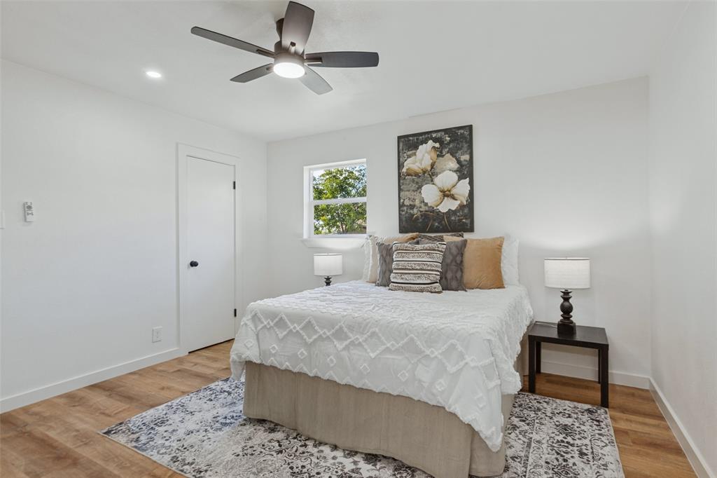 Room featuring wood-finish flooring, a multi-blade ceiling fan with integrated lighting, and a single-panel interior door