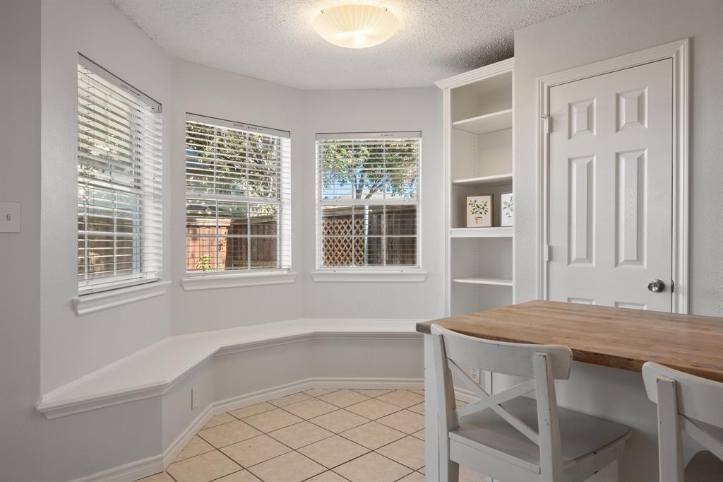 Bay window featuring a built-in bench, ceramic tile flooring, built-in shelving, and dual-pane windows with horizontal blinds