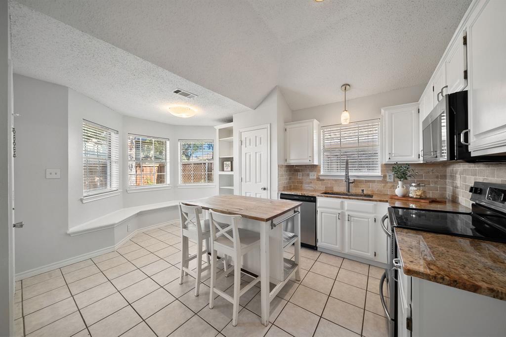 Kitchen featuring stone countertops, white cabinetry, tile flooring, a built-in window seat, and vaulted ceilings