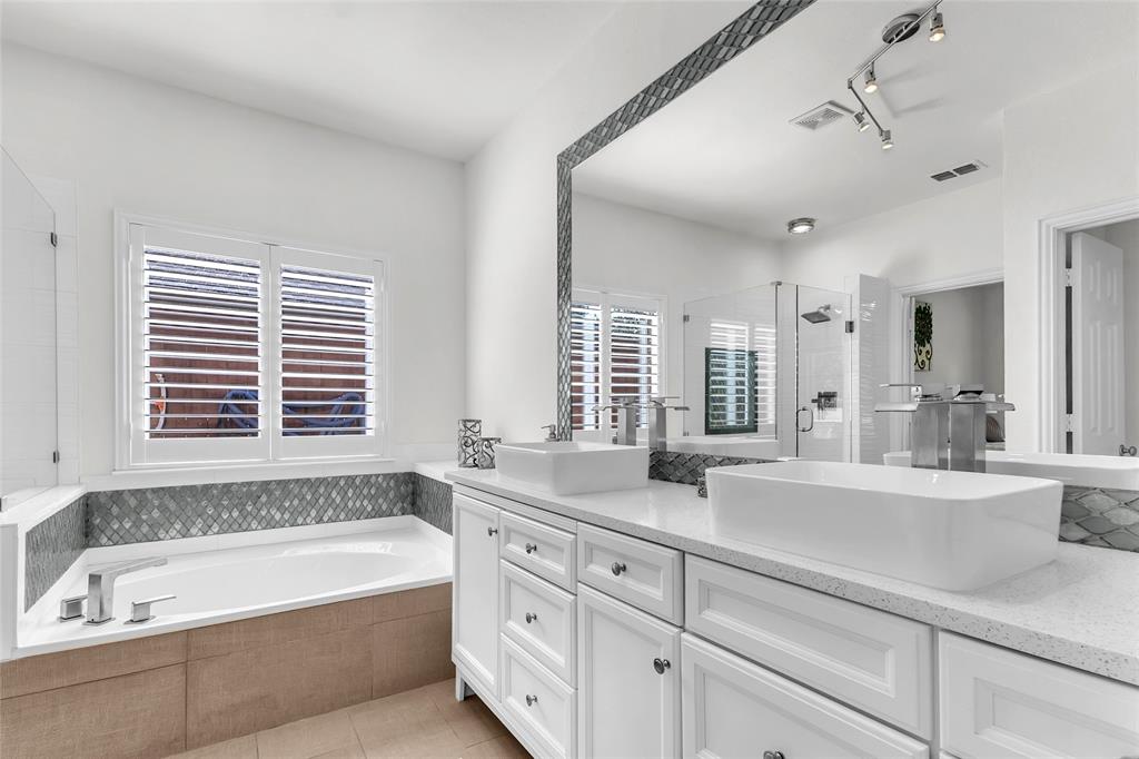 Primary bath with dual vessel sinks, white vanity, and soaking tub — 5804 Lafayette Dr, Frisco