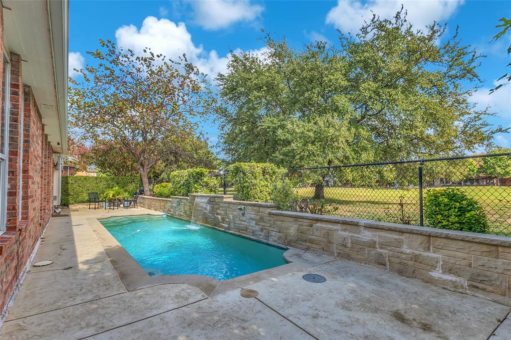 Pool with sheer-descent water feature and golf course beyond the fence — 5804 Lafayette Dr, Frisco