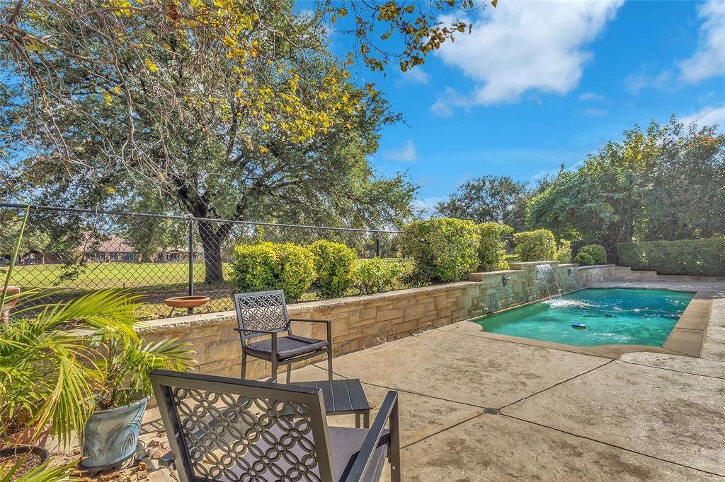 Patio seating by the pool with stone wall and golf course views — 5804 Lafayette Dr, Frisco