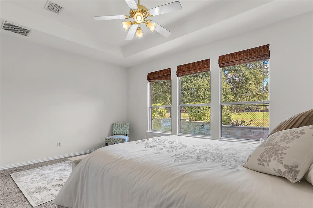 Primary bedroom with tray ceiling and windows facing the golf course — 5804 Lafayette Dr, Frisco