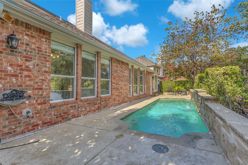 In-ground pool with water feature on stone retaining wall — 5804 Lafayette Dr, Frisco