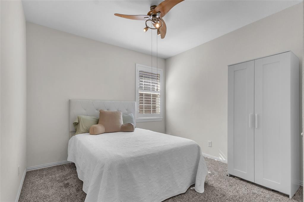 Secondary bedroom with carpet, ceiling fan, and shuttered window — 5804 Lafayette Dr, Frisco
