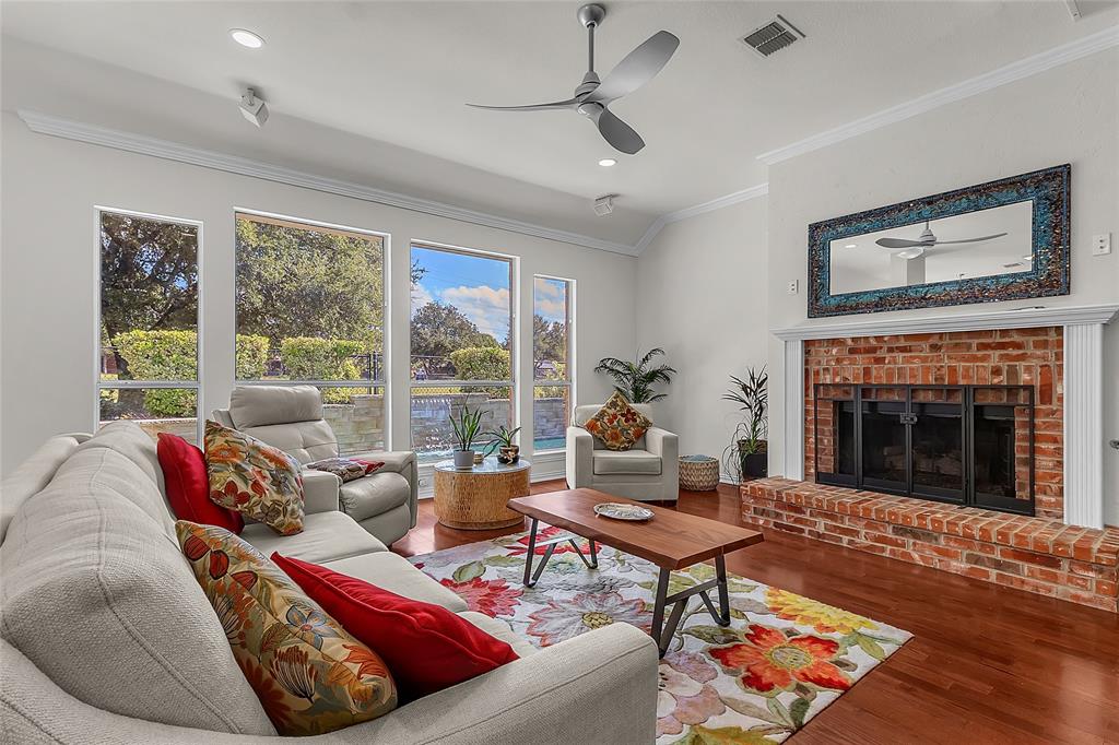 Living room with brick fireplace and wall of windows facing the pool — 5804 Lafayette Dr, Frisco