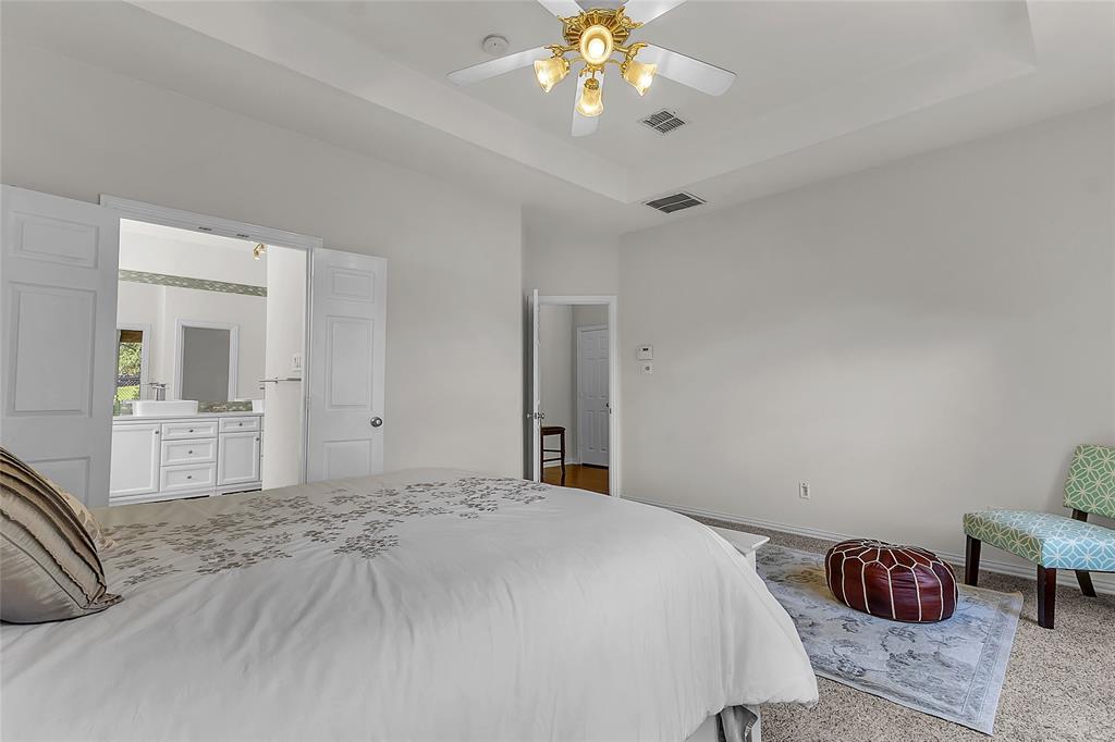 Primary bedroom with tray ceiling, ceiling fan, and bath access — 5804 Lafayette Dr, Frisco