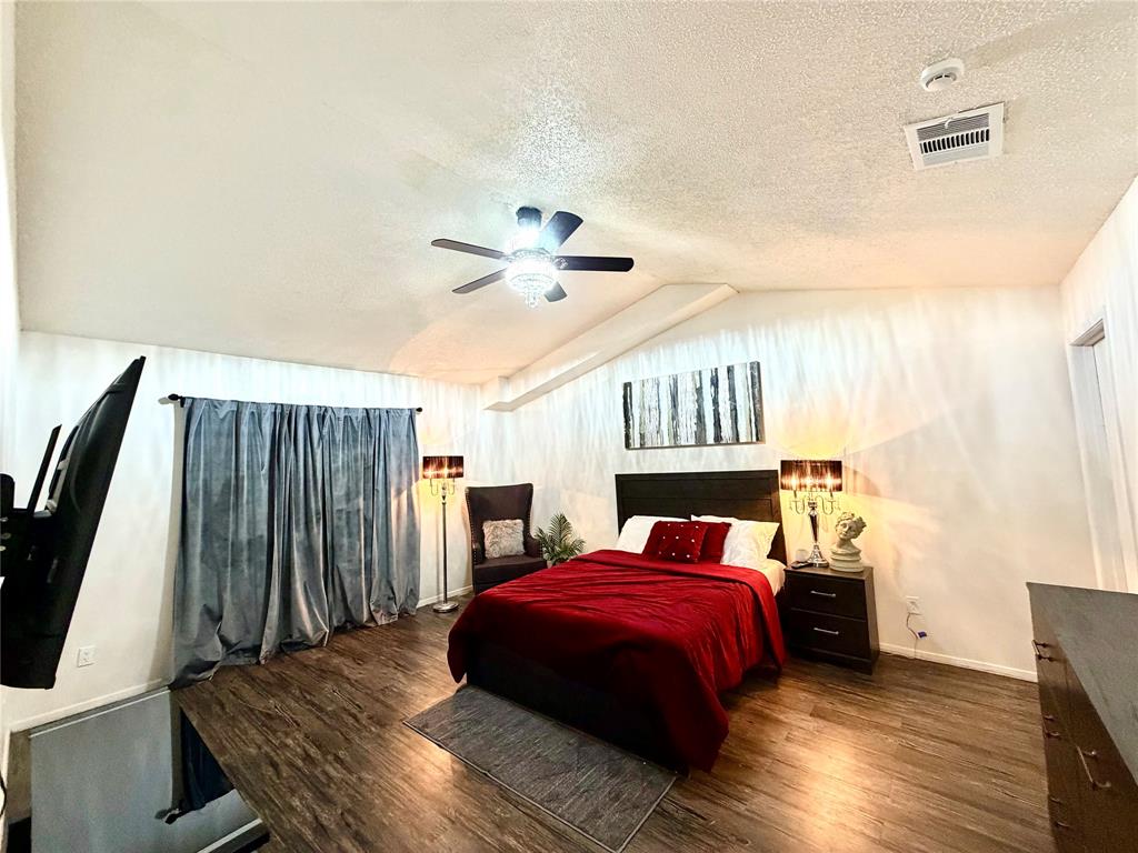 Spacious room featuring vaulted ceilings, wood-finish flooring, and a ceiling fan with integrated lighting Spacious room featuring vaulted ceilings, wood-finish flooring, and a ceiling fan with integrated lighting