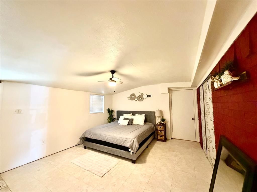 Spacious interior room featuring light-colored flooring, a ceiling fan with integrated lighting, and a window with horizontal blinds