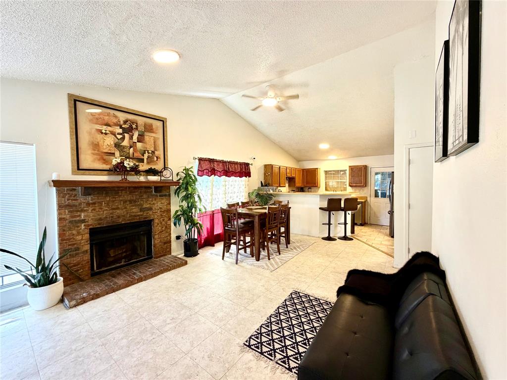 Living area featuring a brick fireplace with a wood mantle, vaulted ceilings, and recessed lighting Living area featuring a brick fireplace with a wood mantle, vaulted ceilings, and recessed lighting