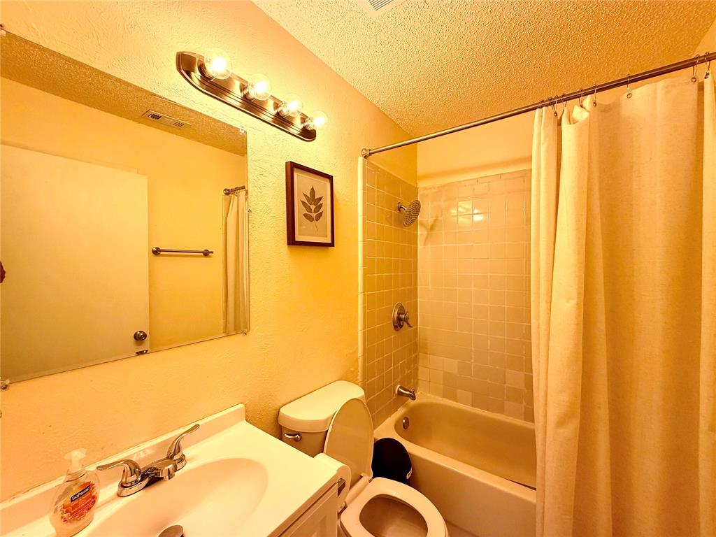 Bathroom featuring a vanity with an integrated sink, a rectangular mirror, a four-bulb vanity light, and a toilet