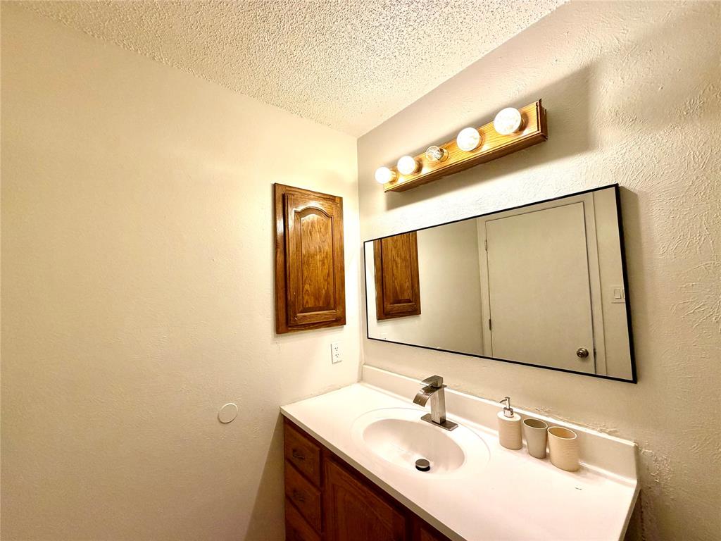 Bathroom vanity featuring a single basin sink, chrome faucet, and white countertop Bathroom vanity featuring a single basin sink, chrome faucet, and white countertop