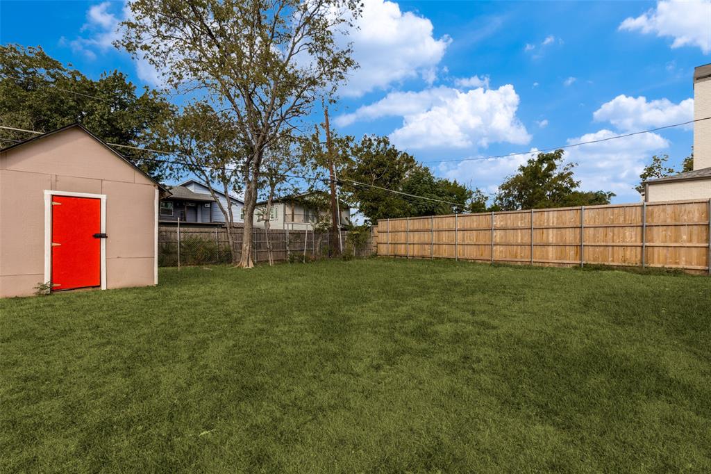Expansive backyard featuring a level lawn, full-perimeter wood fencing, and a detached storage structure