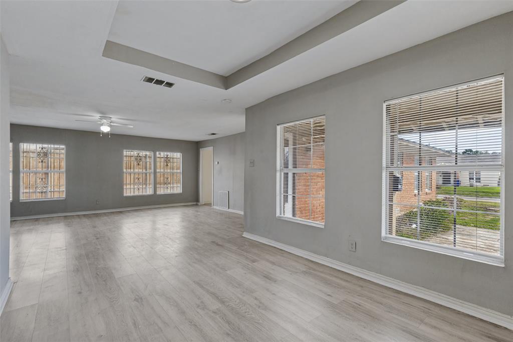 Tray ceiling, wood-finish flooring, multi-pane windows, and ceiling fan with integrated lighting