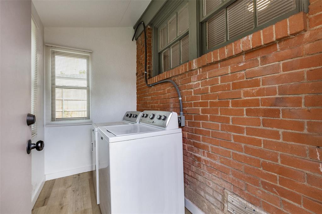 Exposed brick wall, multi-pane windows, wood-finish flooring, and white interior wall finishes