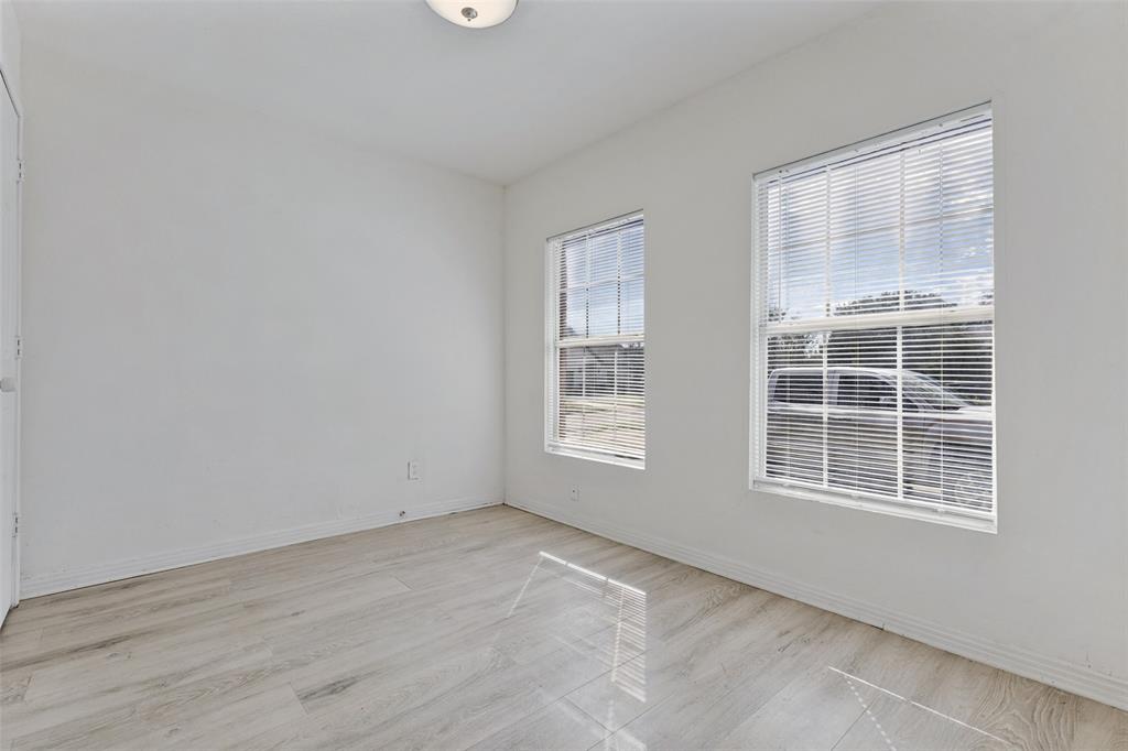 Room featuring wood-finish flooring, two windows with horizontal blinds, neutral wall paint, and a ceiling-mounted light fixture