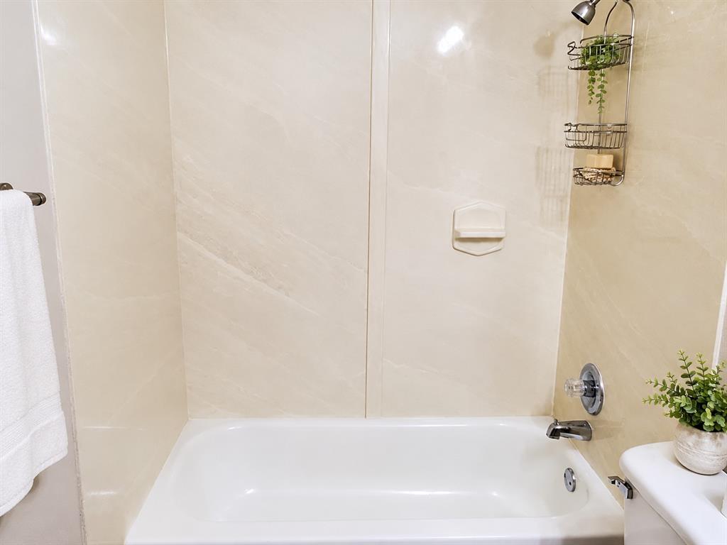 Bathtub surround featuring neutral, large-format paneling, integrated soap niche, and chrome-finish hardware Bathtub surround featuring neutral, large-format paneling, integrated soap niche, and chrome-finish hardware