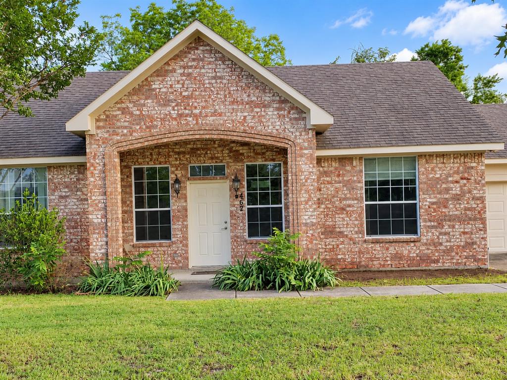 Traditional brick exterior featuring a covered entryway with a decorative arched stone header, multi-pane windows, and a shingled roof Traditional brick exterior featuring a covered entryway with a decorative arched stone header, multi-pane windows, and a shingled roof