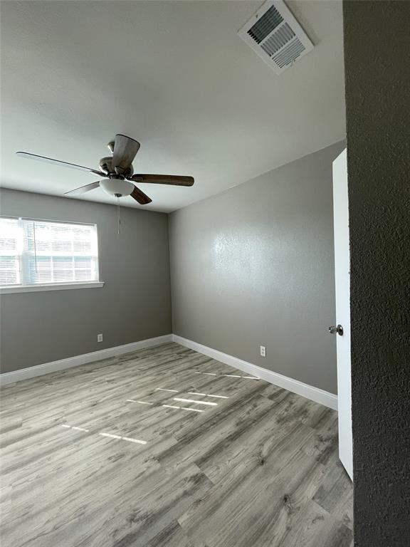 Empty room with light hardwood / wood-style floors and ceiling fan