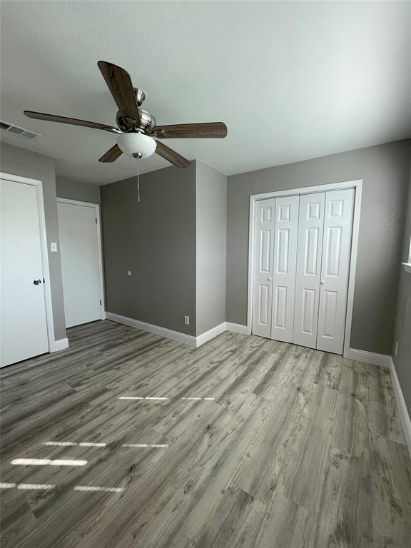 Unfurnished bedroom featuring wood-type flooring, a closet, and ceiling fan
