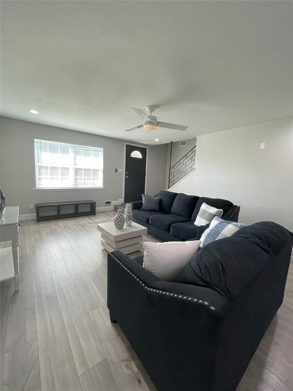 Living room with ceiling fan and light hardwood / wood-style floors