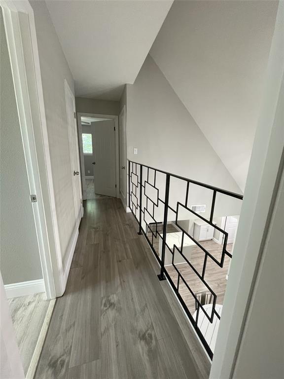 Corridor with lofted ceiling and hardwood / wood-style floors