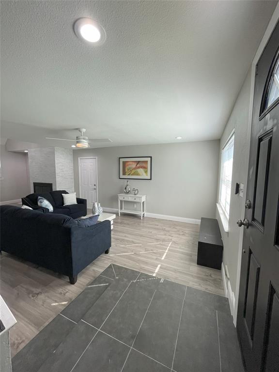 Living room featuring hardwood / wood-style flooring, a textured ceiling, and ceiling fan