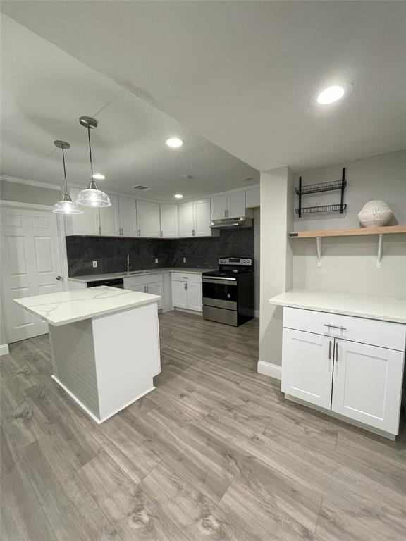 Kitchen featuring white cabinetry, decorative backsplash, sink, stainless steel range with electric stovetop, and light hardwood / wood-style flooring