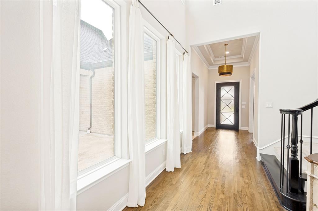 Impressive wide entry hallway with tray ceiling and wall of windows featuring private courtyard. Impressive wide entry hallway with tray ceiling and wall of windows featuring private courtyard.