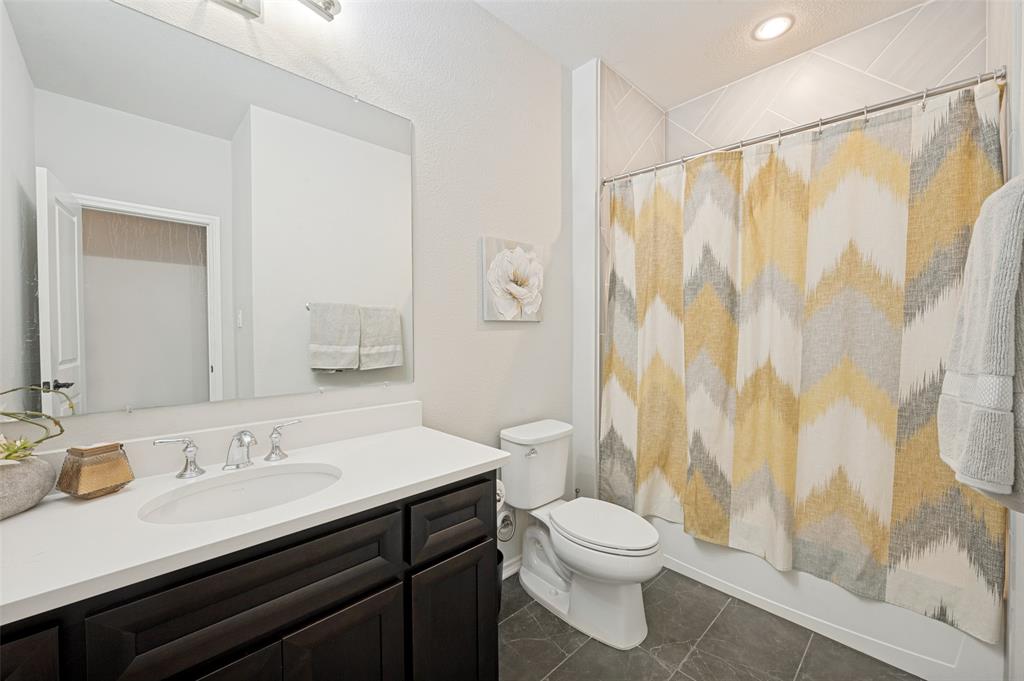 This hallway bathroom features a dark wood vanity and a tub shower.