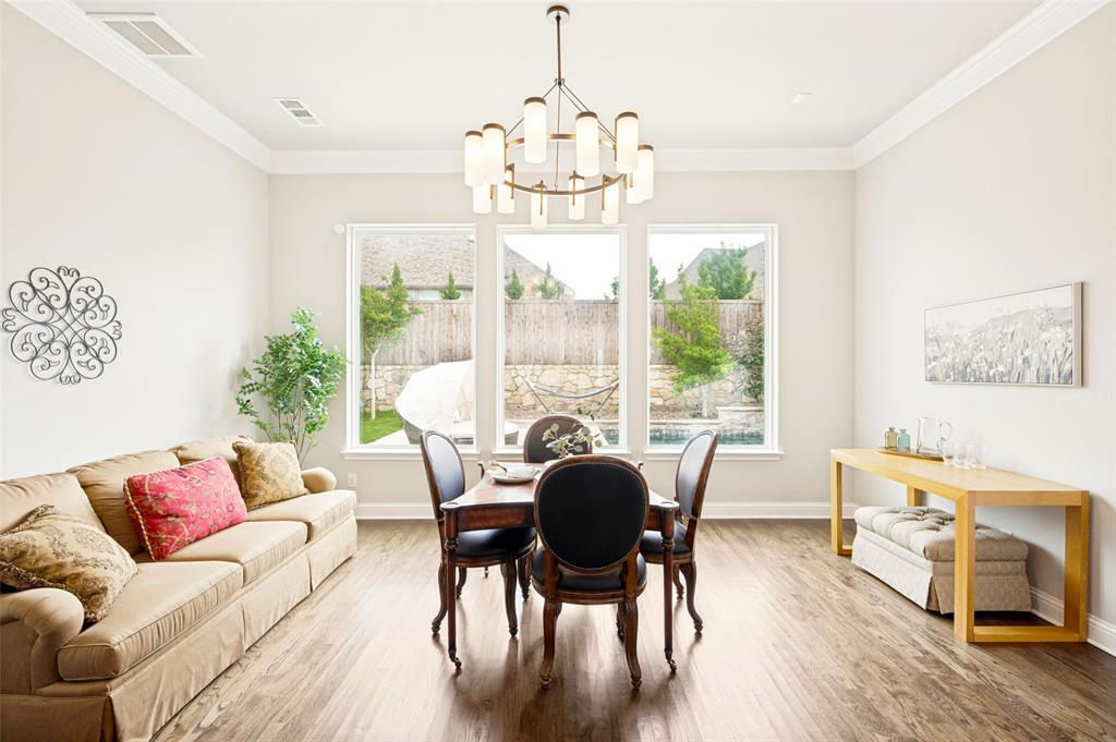Dining area featuring wood flooring, a contemporary chandelier, and three large windows providing abundant natural light