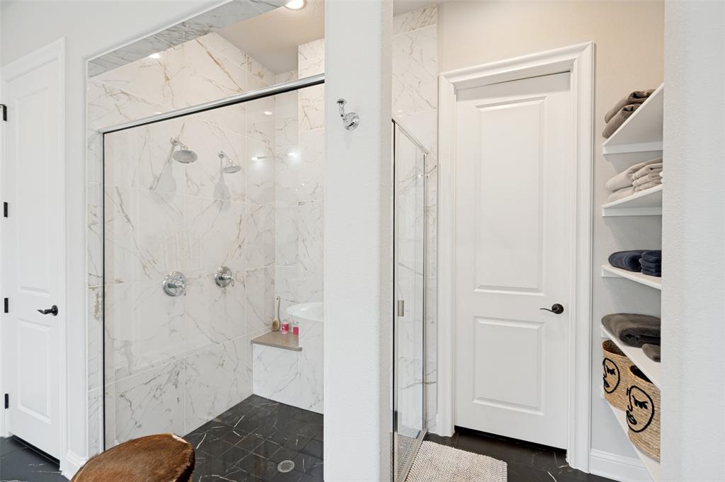Walk-in shower with clear glass enclosure and marbled tile surround. This ensuite also features two walk-in-closets.