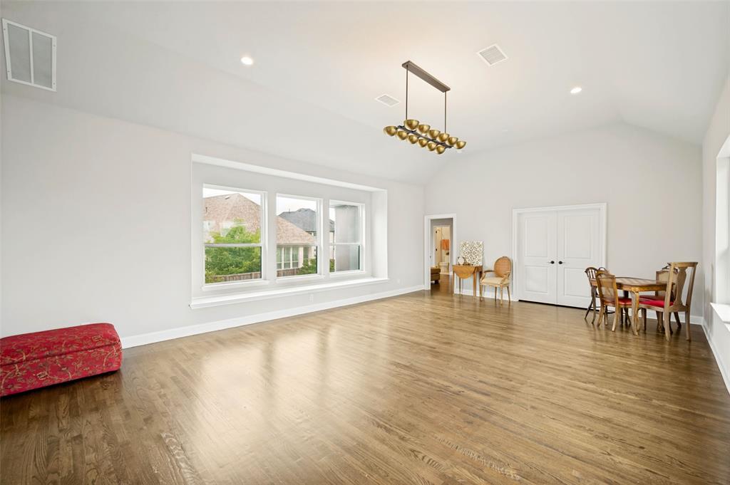 Spacious gameroom featuring vaulted ceilings, wood flooring, a contemporary linear chandelier, recessed lighting, and a multi-pane window with a window ledge.