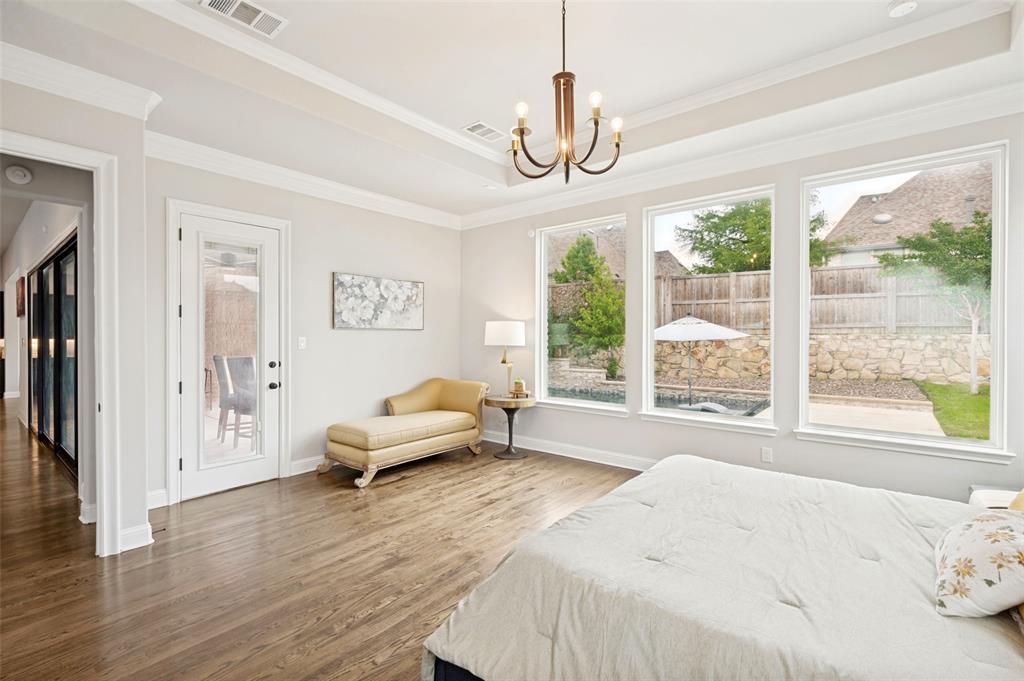 The spacious primary suite provides space for a sitting area and direct access to the patio along with expansive windows overlooking the private backyard and pool