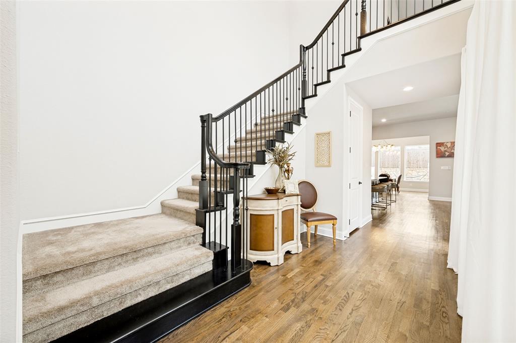 Grand entryway featuring a curved staircase with black newel posts and wrought iron balusters leading to open living area. Grand entryway featuring a curved staircase with black newel posts and wrought iron balusters leading to open living area.