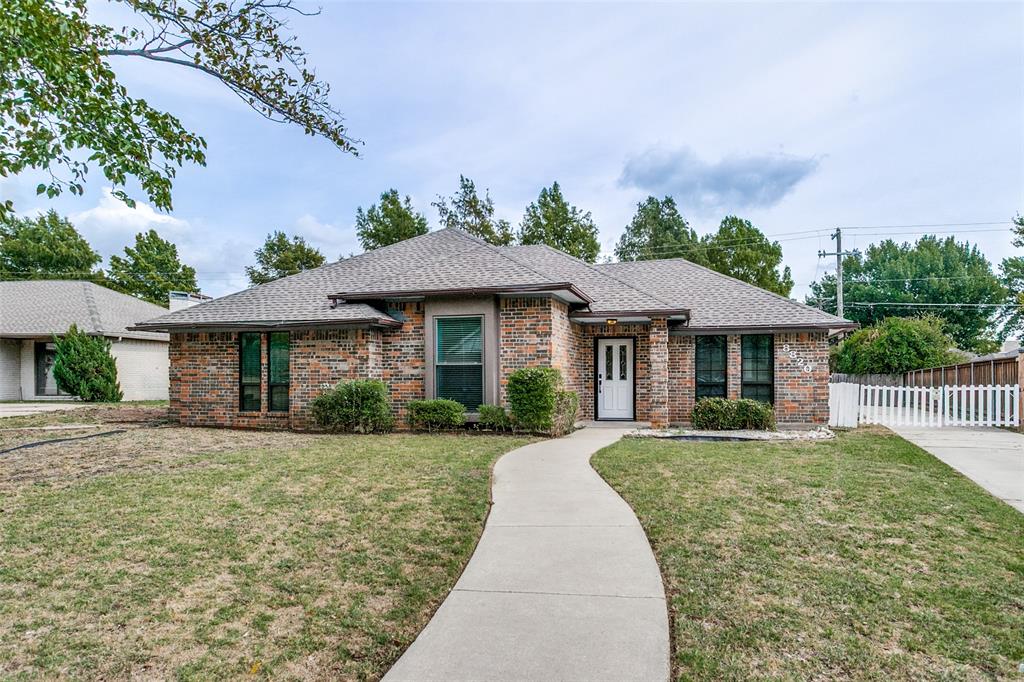 Single-story brick exterior featuring a multi-gabled roofline, concrete walkway, and white-paneled entry door with sidelights Single-story brick exterior featuring a multi-gabled roofline, concrete walkway, and white-paneled entry door with sidelights