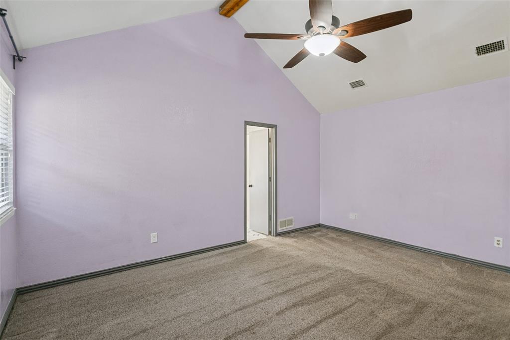 Vaulted ceilings featuring a central wooden beam, neutral wall finish, wall-to-wall carpeting, and an integrated ceiling fan with light fixture