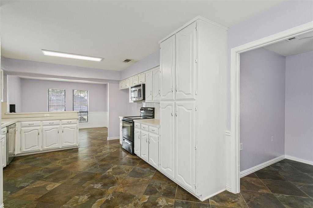 Kitchen featuring white cabinetry, tall built-in pantry storage, stone-tile flooring, and built-in appliances