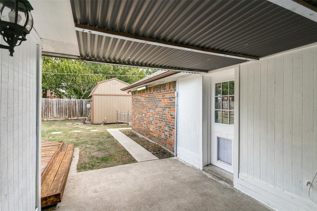 Covered patio with corrugated metal roofing, wood-finish exterior siding, brick masonry, and a concrete patio floor