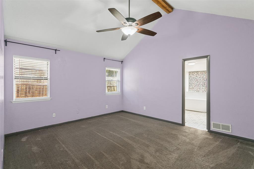 Vaulted ceiling featuring a natural wood-finish beam, carpeted flooring, and a central ceiling fan with an integrated light fixture