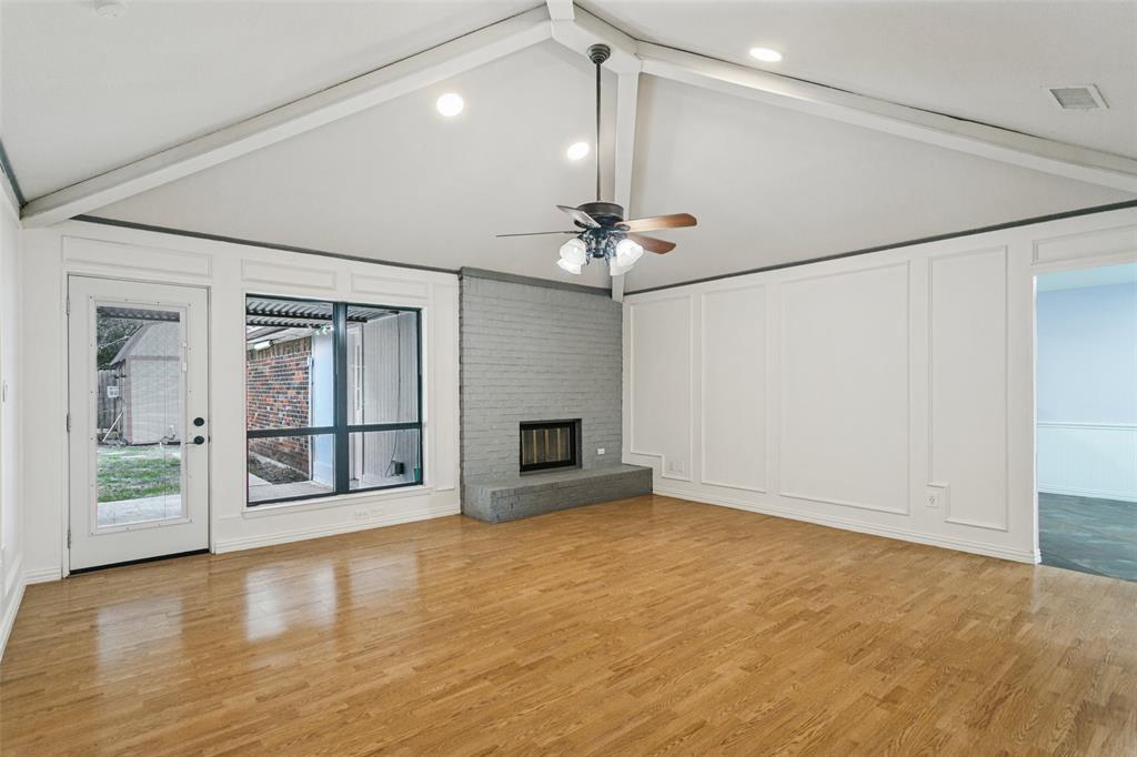 Vaulted ceiling with exposed beams, wood-finish flooring, painted brick fireplace with raised hearth, wainscoting wall paneling, and recessed lighting Vaulted ceiling with exposed beams, wood-finish flooring, painted brick fireplace with raised hearth, wainscoting wall paneling, and recessed lighting