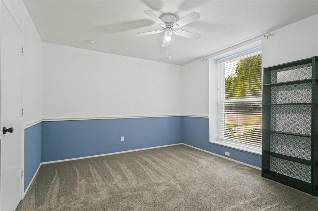 Neutral-toned carpeting, two-toned wall paint with chair rail molding, ceiling fan with light kit, and a large window with horizontal blinds