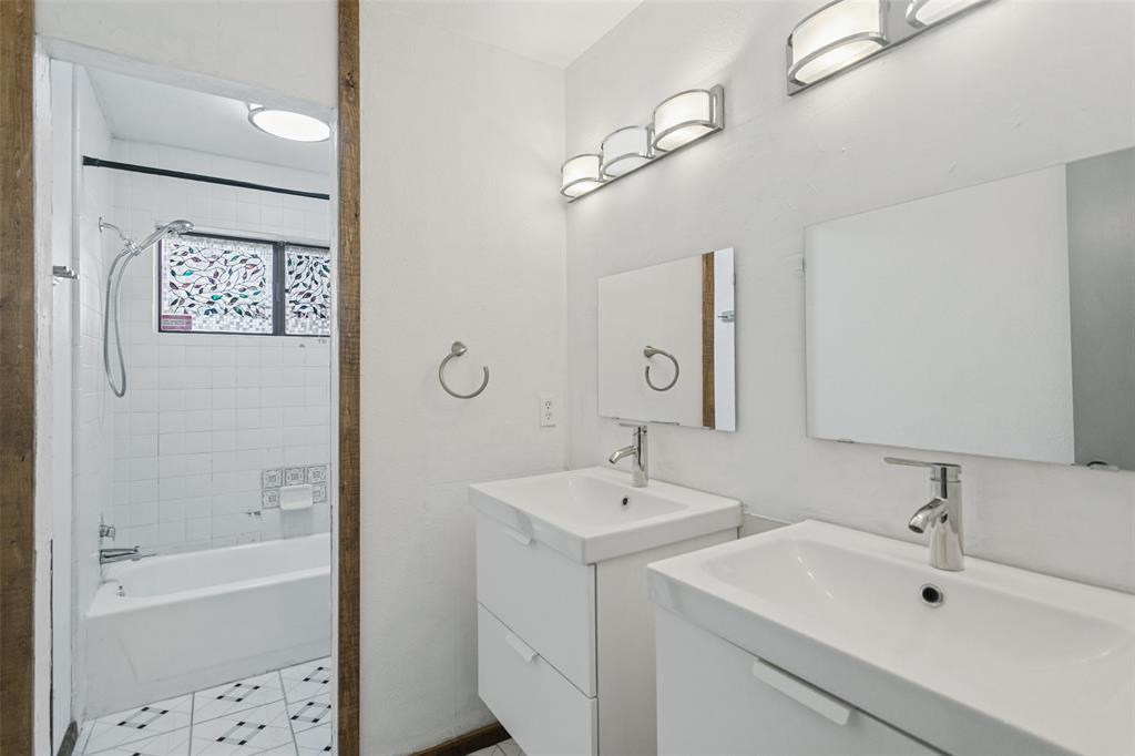 Double vanity featuring wall-mounted square mirrors and integrated rectangular sinks, complemented by contemporary polished chrome hardware, multi-light vanity fixtures, and a tiled shower-tub combination