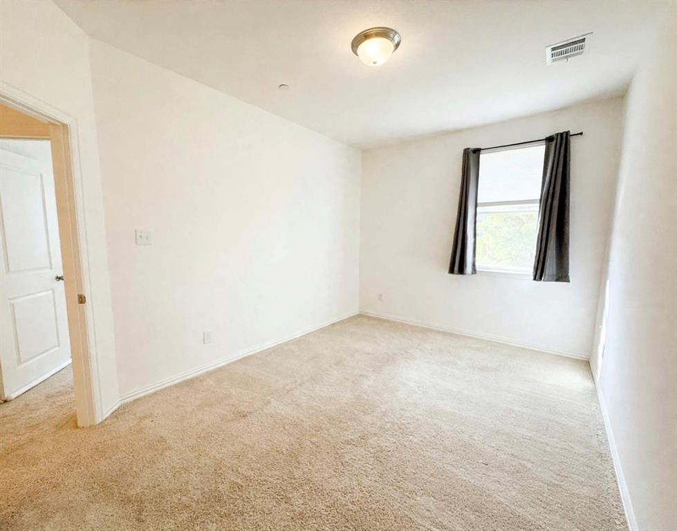 Neutral-toned carpeted flooring, white interior walls, flush-mount ceiling lighting, and a single-pane window