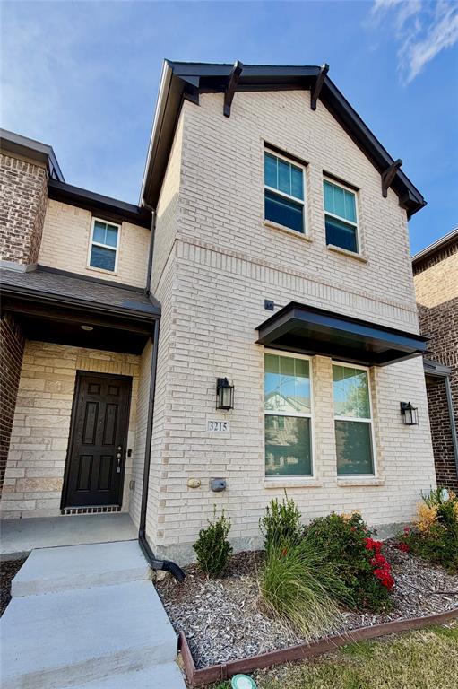 Two-story brick exterior featuring a dark metal door awning, multi-pane windows, and a concrete walkway