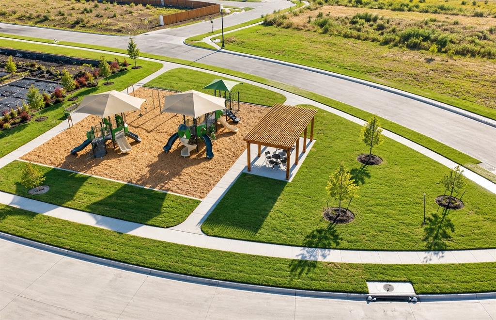 Recreational area featuring a playground with shade structures, a wooden pergola, manicured lawn, and paved walkways