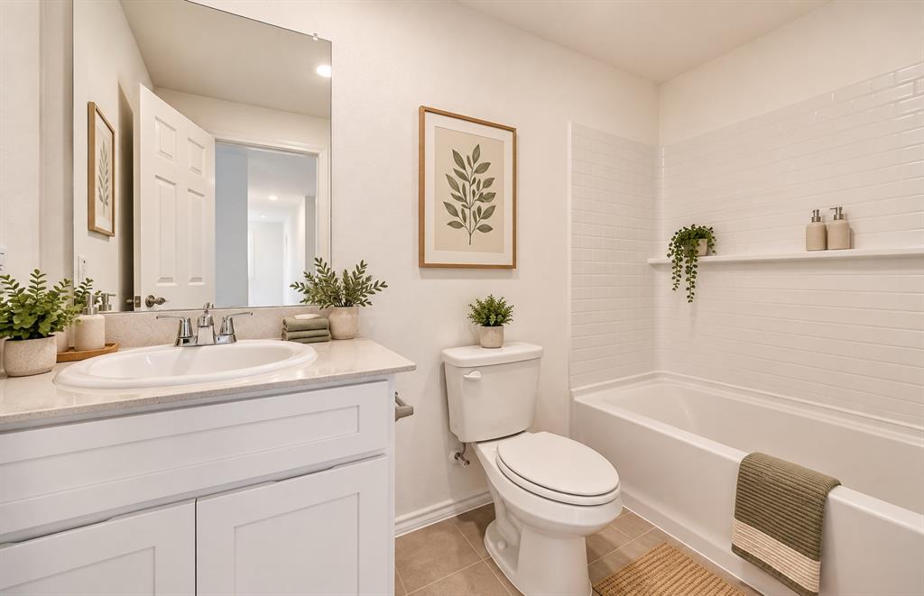 Bathroom featuring a white vanity cabinet with a stone-finish countertop, undermount sink, subway tile shower surround, and a large wall-mounted mirror