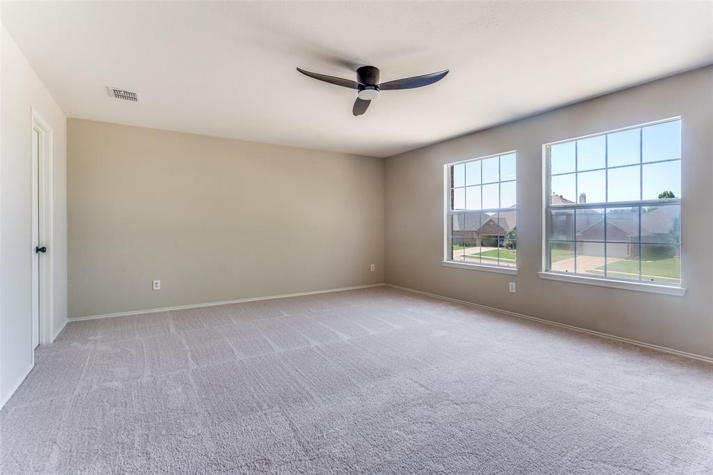 Neutral-toned interior space featuring light-colored wall-to-wall carpeting, dual double-pane windows, and a multi-blade ceiling fan
