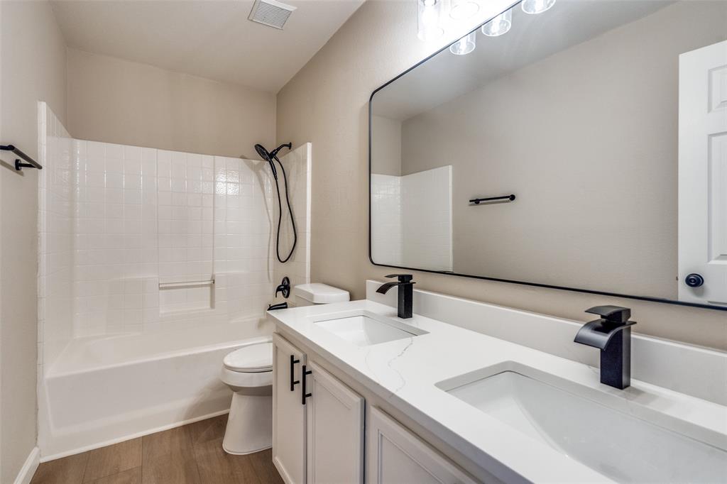 Dual vanity with a white composite countertop, undermount sinks, matte black widespread faucets, large rectangular wall mirror, and wood-finish flooring